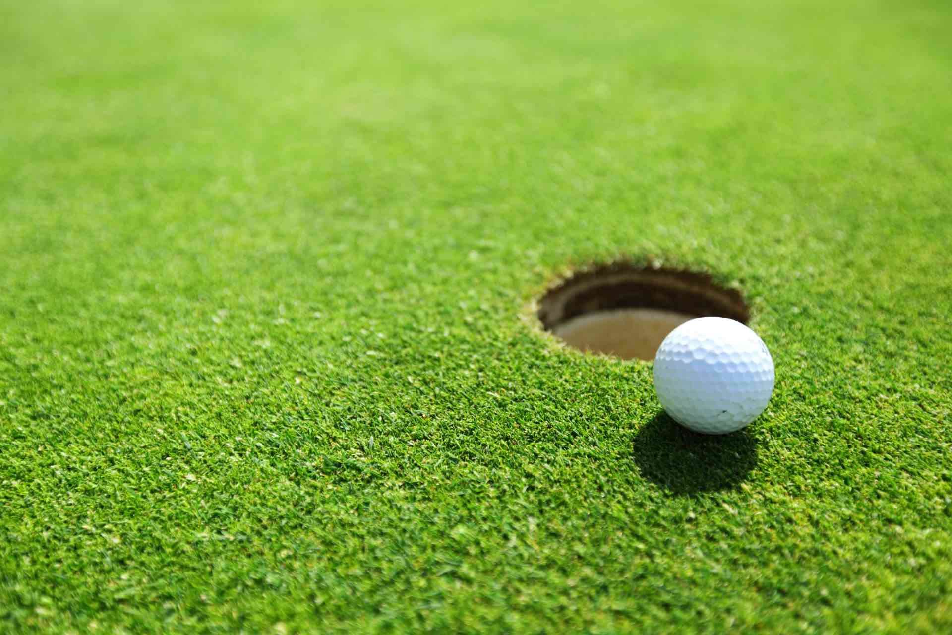 white golf ball next to a golf hole